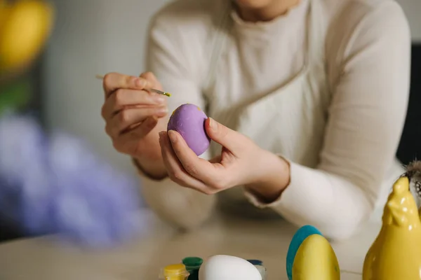 Middle selection of young woman painting Easter eggs in the kitchen. Spring holidays. High quality photo
