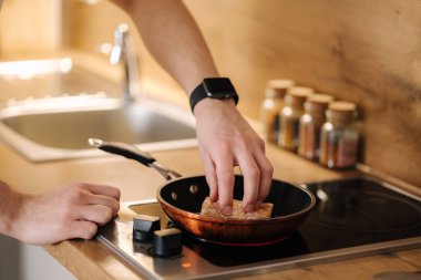 İnsan eli ısıtılmış tavaya bir dilim baget koyar. Ev yapımı yemek konsepti. Yüksek kalite fotoğraf