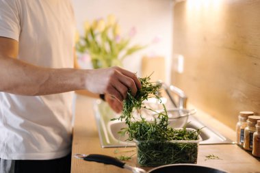 İnsan elinin yan görünüşü bir demet roka alır ve suyla durulanır. Yüksek kalite fotoğraf