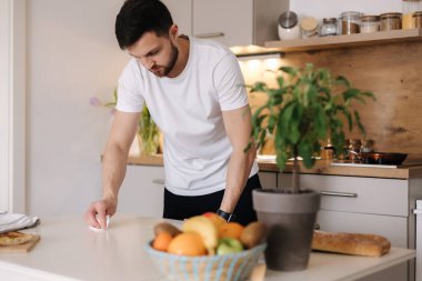 Genç adam yemek yaptıktan sonra mutfakta masaları temizler. Yüksek kalite fotoğraf