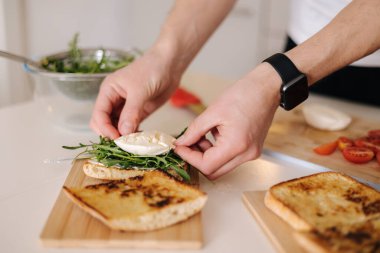İnsan eli roka soslu sandviçe mozzarella koyuyor. Klasik İtalyan yemeği. Yüksek kalite fotoğraf