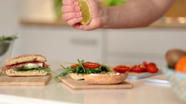 İnsan eli vejetaryen sandviçe limon sıkıyor. Vegan ev yapımı başlık konsepti. Yüksek kalite 4k görüntü