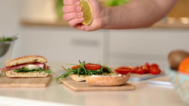 人間の手はビーガンサンドイッチにレモンを絞る ビーガンホームフードの概念を作った 高品質4K映像 — ストック動画