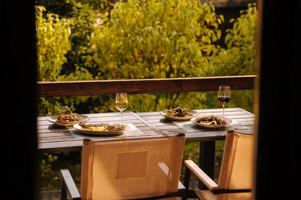 Outdoor dinner on summer terrace. Served table with several dishes. Tasty food in restaurant. High quality photo