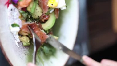 Kadının orta seçim somon tostu kesmek için çatal ve bıçak kullanır. Lokantada kahvaltı. Dikey video. Yüksek kalite 4k görüntü