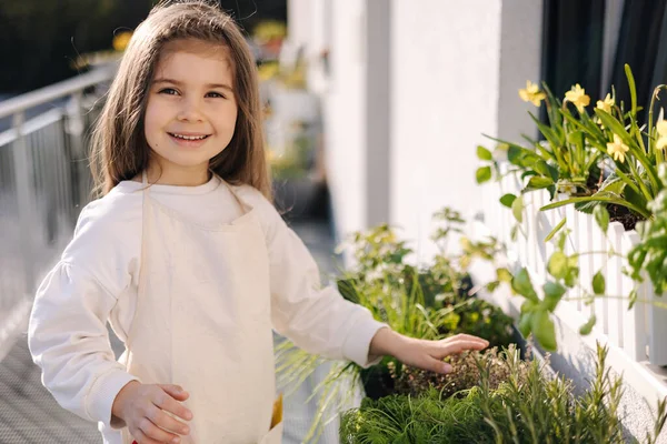 stock image Portrait of adorable four year old girl gardening on balcony. Long-haired little girl in beautiful overall . High quality photo