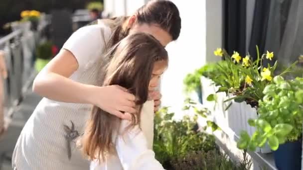 Красивая Молодая Мама Помогает Своей Дочери Одеться Целом Садоводства Балконе — стоковое видео