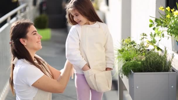 Bella Giovane Mamma Aiuta Figlia Vestirsi Generale Giardinaggio Sul Balcone — Video Stock