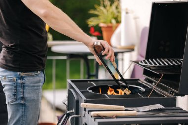 Yakışıklı bir adam ateş yakar ve süreci kontrol eder. Barbekü ızgarası dışarıda. Yüksek kalite fotoğraf
