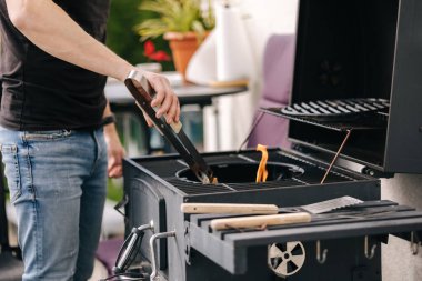 Yakışıklı bir adam ateş yakar ve süreci kontrol eder. Barbekü ızgarası dışarıda. Yüksek kalite fotoğraf