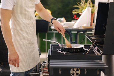 Yakışıklı adam dışarıda ızgarada yemek pişiriyor. Adam kızartma tavasında yemek pişiriyor. Açık havada yaz yemeği. Yüksek kalite fotoğraf