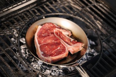 Lezzetli biftek sıcak kömürlerin üzerinde duran karbon çelik bir tavada kızartılır. Mangal konsepti. Yüksek kalite fotoğraf