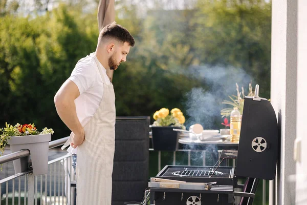 Adam açık havada önlük giyiyor. Barbekü ızgarasına hazırlanıyorum. Yüksek kalite fotoğraf