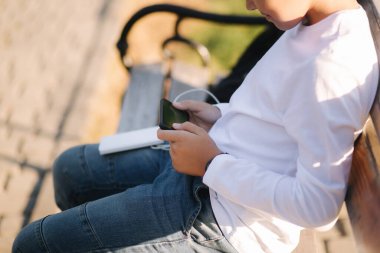 Beyaz tişörtlü genç çocuk akıllı telefonunu şarj etmek için Power Bank kullanıyor. Akıllı telefonun şarjı az..