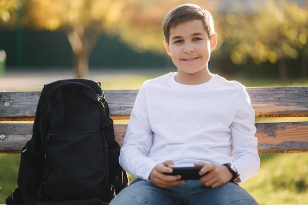 十几岁的男孩在学校下课后在公园里用智能手机玩网络游戏 — 图库照片