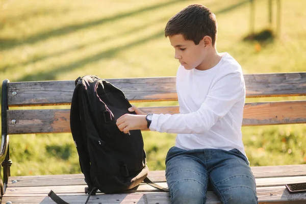 携帯電話を充電するために彼のバックパックのパワーバークからハンサムな十代の男の子を取る 秋の公園でかわいい男の子 — ストック写真