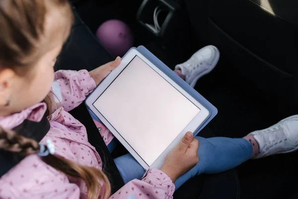 在汽车座椅上用数字平板电脑模仿小女孩 和家人一起旅行高质量的照片 — 图库照片