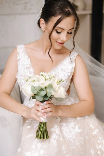 豪華な花嫁は彼女の目を閉じて 美しい化粧を示しています 女性はエレガントなウェディング花束を手に持ち 椅子に座っています 高品質の写真 — ストック写真