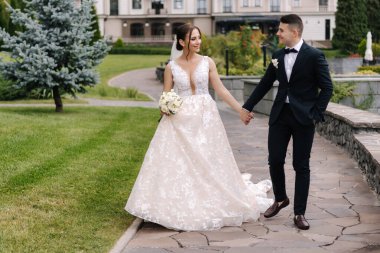 Mutlu yeni evliler el ele tutuşup arazide dolaşırlar. Muhteşem bir çift damat ve gelin gülüşü. Yüksek kalite fotoğraf