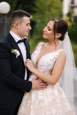 Dışarıda duran yakışıklı damat ve muhteşem gelin portresi. Gelin buketi. Erkek ve kadın birbirine sarılır. Yüksek kalite fotoğraf