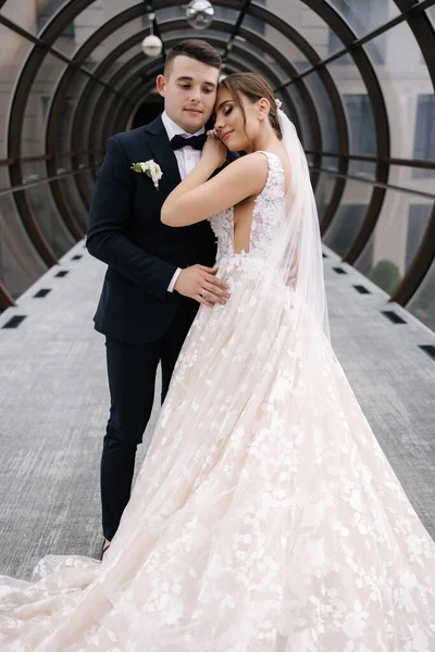 窓のある大きなホールで美しい結婚式のカップル エレガントな花嫁と新郎が抱き合っています 高品質の写真 — ストック写真