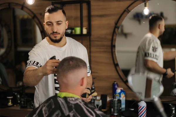Handsome man on a haircut in the barber sits on a chair. High quality photo