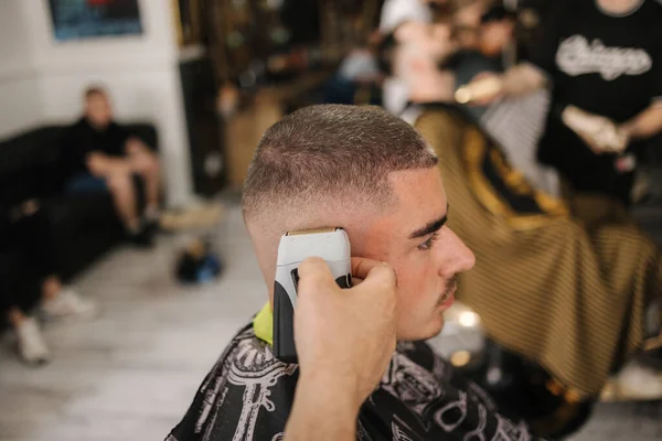 Handsome man on a haircut in the barber sits on a chair. High quality photo