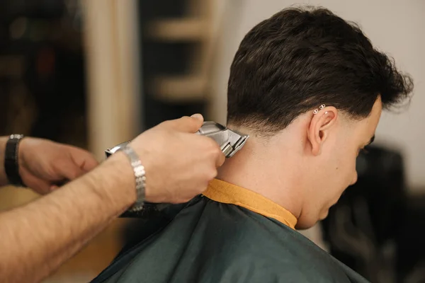 Barber use trimmer to cut hair of man. Back view of male client sitting . High quality photo