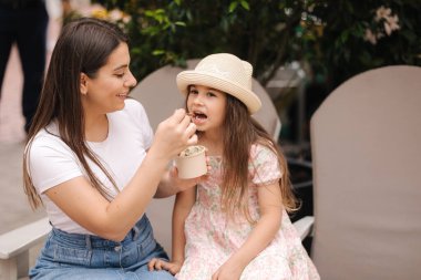 Anne ve kızı dondurma yerken eğleniyorlar. Alışverişten sonra dinlenin. Yüksek kalite fotoğraf