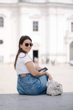 Taştan bankta oturan ve telefon kullanan bir kadının arka görüntüsü. Yüksek kalite fotoğraf