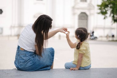 Anne ve kızının arka planı oturur ve elleriyle bir kalp sembolü yapar. Yüksek kalite fotoğraf