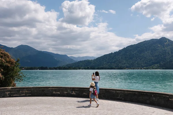 stock image Side view of woman walk and takes a video on phone. Beautiful turquoise clear water. Family holiday. Mom and daughter . High quality photo