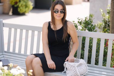 Kadın çantadan bir şey alırken çekilmiş bir fotoğraf. Siyah elbiseli genç bir kadın. Yüksek kalite fotoğraf