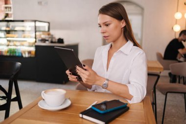 Kafede dijital tablet kullanan serbest çalışan bir kadın. Genç işletme müdürü iş arasında kahve içer. Yüksek kalite fotoğraf
