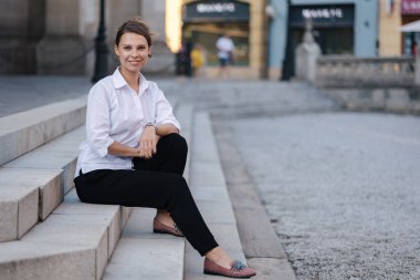 Resmi kıyafetli kadın portresi merdivenlerde oturur. Kadın işten sonra vakit geçirmiş. Yüksek kalite fotoğraf