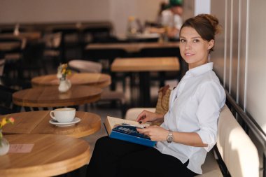 Kafede kitap okuyan bir kadının yan görüntüsü. Yüksek kalite fotoğraf