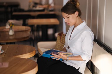 Güzel bir kadın kafede oturur ve kitabı okur. Kadınlar işten sonra vakit geçirir. Yüksek kalite fotoğraf