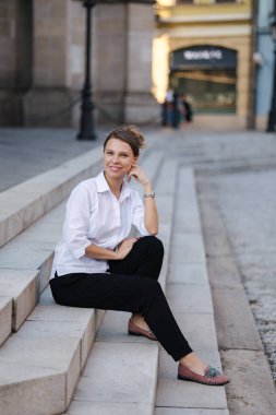 Resmi kıyafetli kadın portresi merdivenlerde oturur. Kadın işten sonra vakit geçirmiş. Yüksek kalite fotoğraf