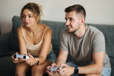 Nişanlısı olan yakışıklı çocuk joystickle video oyunu oynuyor. Adam kız arkadaşına nasıl konsol oynanacağını öğretiyor. Yüksek kalite fotoğraf