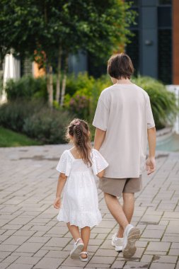 Küçük kız kardeşinin ağabeyiyle yürüyüşünün arka görüntüsü. Mutlu aile kavramı. Yüksek kalite fotoğraf
