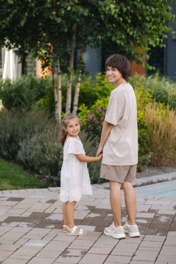 Küçük kız kardeşinin ağabeyiyle yürüyüşünün arka görüntüsü. Mutlu aile kavramı. Yüksek kalite fotoğraf