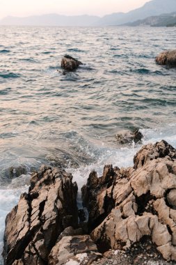 Bir deniz dalgası kıyıdaki bir taşa ve kayaya çarpıyor. Deniz batımı. Yüksek kalite fotoğraf
