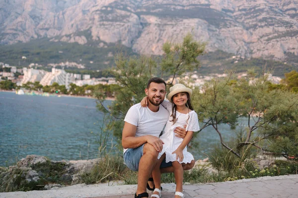 stock image Adorable little daughter with her lovely father. Portrait of happy family in front of mountains and sea. High quality photo