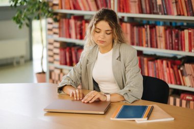 Genç kız öğrenci bilgisayarı açar ve halk kütüphanesinde çalışmaya başlar. Üniversite sınavına hazırlanan kadın. Yüksek kalite fotoğraf