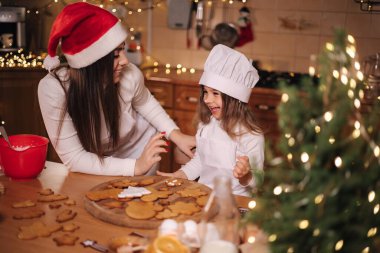 Anne ve küçük tatlı kızı Noel arifesinde mutfakta vakit geçiriyorlar. Kızlar tatil için tatlı hazırlıyor. Zencefilli çörek ve şeker. Mutlu aile.
