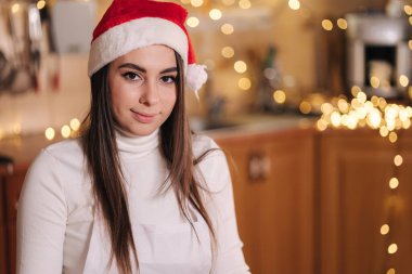 Mutfakta Noel Baba şapkalı çekici genç annenin portresi. Noel tatili.