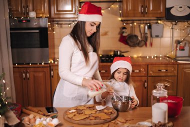 Anne ve küçük tatlı kızı Noel arifesinde mutfakta vakit geçiriyorlar. Kızlar tatil için tatlı hazırlıyor. Zencefilli çörek ve şeker. Mutlu aile.