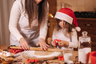 Anne ve kızı zencefilli ekmek yapmak için merdane kullanıyorlar. Zencefilli ekmek için hamurun en iyi görüntüsü. Noel havası. Tatil hazırlığı.