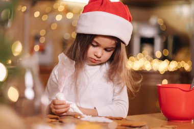 Anne ve küçük tatlı kızı Noel arifesinde mutfakta vakit geçiriyorlar. Kızlar tatil için tatlı hazırlıyor. Zencefilli çörek ve şeker. Mutlu aile.