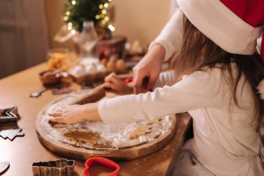 Evde zencefilli ekmek yapıyorum. Annesiyle küçük bir kız zencefilli kurabiye hamuru kesiyor. Noel ve Yeni Yıl gelenekleri. Noel pastanesi. Mutlu tatiller..